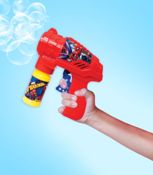 The boy holds a water gun on a pink background.